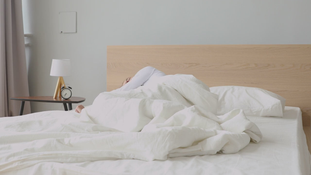 Load video: Frau wacht erholt in einem modernen Schlafzimmer mit ruhiger Morgenstimmung auf